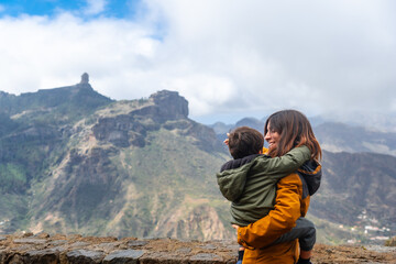 A mother with her son looking at Roque Nublo from a viewpoint. Gran Canaria, Spain - obrazy, fototapety, plakaty