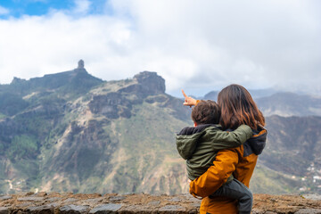 A mother with her son looking at Roque Nublo from a viewpoint. Gran Canaria, Spain
