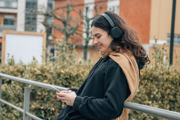 teenager girl with headphones on the street in winter
