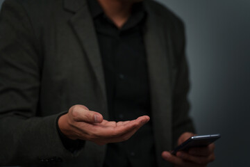 businessman with empty hand and open palm offering something while using smartphone