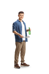 Young man holding a barbecue turner and a bottle of beer - obrazy, fototapety, plakaty