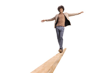 Young man with curly hair walking on a wooden beam and smiling - obrazy, fototapety, plakaty