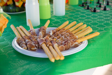 Closeup shot of breadsticks with ham on a green table