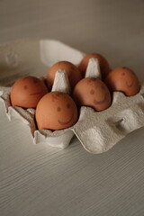 Vertical shot of eggs with painted emotions in an egg carton