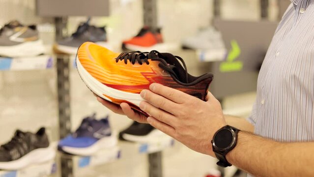 Close up of man buyer choosing new sneakers at sports store