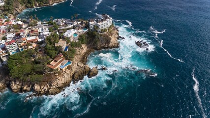Aerial drone view of Acapulco Bay lines with high residential buildings in rocky coastline