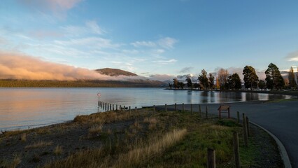 Asphalt road leading to a lake in New Zealand at sunset