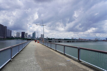 Naklejka premium Walking bridge in the background of a cityscape on a cloudy day