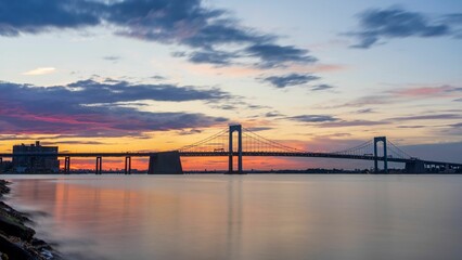 Beautiful shot of a sea with the background of a bridge silhouette and the sunset sky