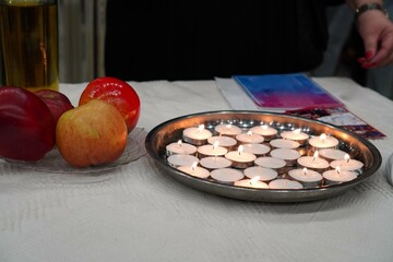symbolic Shabbat - lighted candles with Sabbath food, a collection of Shabbat sindur on a wooden table with a cotton white tablecloth