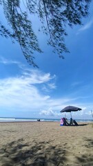 Vertical shot an umbrella on a sandy beach against the sea on a sunny day in Pangandaran, Indonesia