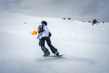 Snowboarder in action on snowy slope, dressed in winter sports gear with bright orange shovel....