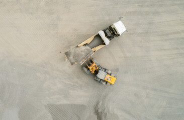 Sand loaders are shoveling rocks into dump trucks. - 781192733