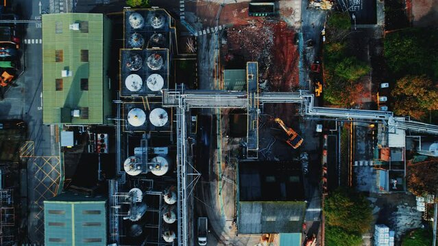 Aerial top view footage of a cran and other equipment working in an industrial area of factories