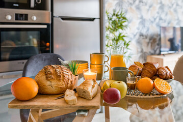 petit déjeuner avec fruits pains croissants et café installé sur une table de cuisine