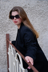 young blonde woman in a black classic jacket and black stylish sunglasses on the street. close-up portrait of a blonde woman. casual style
