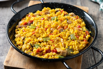 Yellow rice with chicken and vegetables on wooden table - 781206303