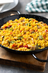 Yellow rice with chicken and vegetables on wooden table