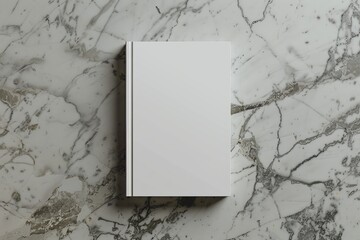 A white book is sitting on a marble countertop. The book is empty and has no writing on it
