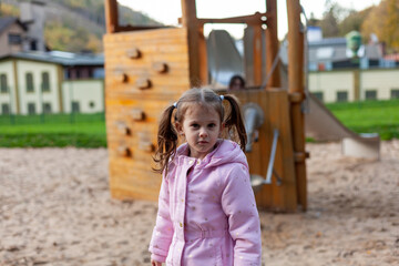 a little warmly dressed girl with two ponytails plays on the playground