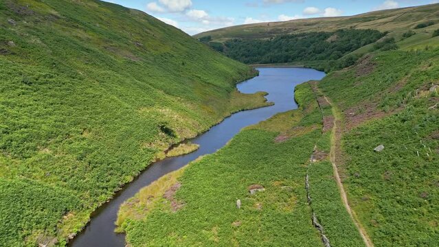 Drone view over a narrow river flowing between green landscapes