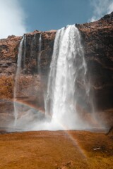 Vertical shot of a beautiful waterfall with a rainbow in Iceland