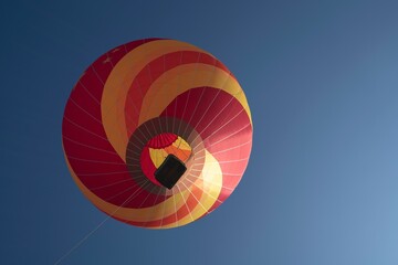 Low-angle shot of a red and yellow hot air balloon in the clear sky