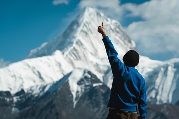 Young boy sightseeing the snow-covered peak of an Alpine mount and posing with a thumbs up