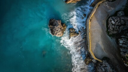 Top drone view of the rocky beach against the azure sea