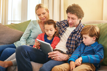 Family, tablet and together on couch for watching with happiness, internet connection and rapport. Parents, young children and tech on sofa in living room for streaming with relax, online and smile