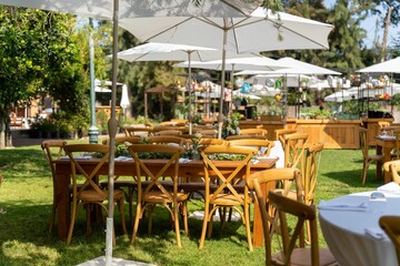 Tables under the white parasols decorated with delicate bouquets prepared for the wedding ceremony