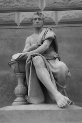 Vertical shot of a statue of a man sitting by Prague's National Museum wearing an ancient mantle