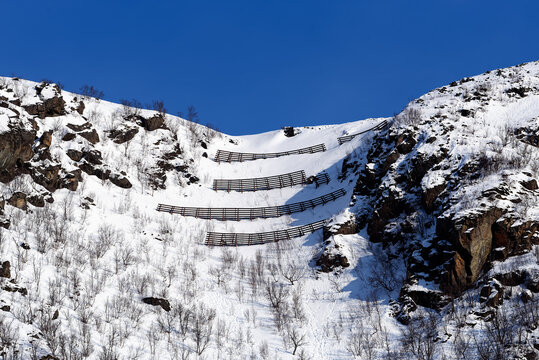 Avalance fences on top of a hill above small city of Øksfjord in Finnmark in Northern Norway on sunny march afternoon in 2024.