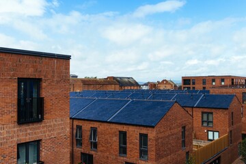 View of red brick buildings under a blue sky with clouds.