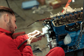 Closeup shot of a young Caucasian mechanic mounting the car engine