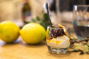 Shallow focus shot of a creamy mousse with dried fruits in it with lemons in the background