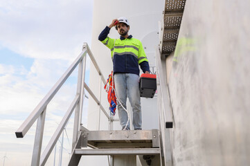 Portrait of engineer wearing yellow vest and white hat on site at wind farm or solar cell farm and energy sustainable energy concept
