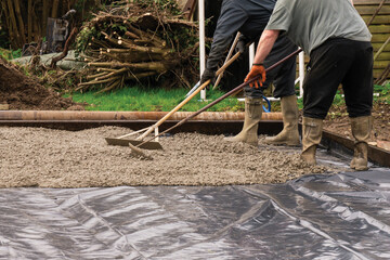 Placing freshly poured concrete with a rake within the form work. - obrazy, fototapety, plakaty