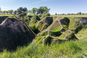 Deep narrow ravine with steep clay slopes among flat terrain