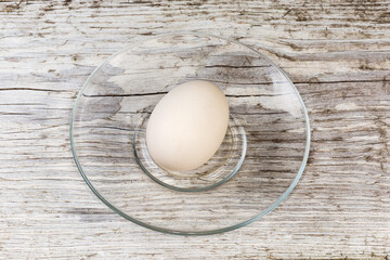 Whole boiled white chicken egg on glass saucer