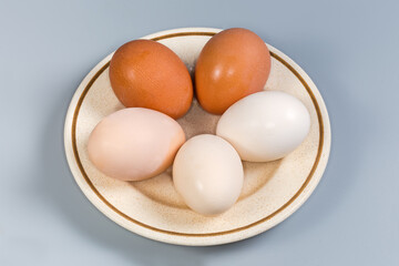 Whole boiled chicken eggs different colors on a saucer