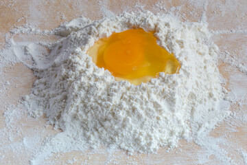 Broken egg on a heap of wheat flour close-up