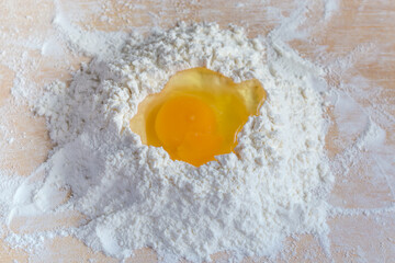 Broken egg on a heap of wheat flour top view - 781234583