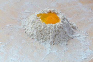 Broken egg on heap of wheat flour on wooden board - 781234589