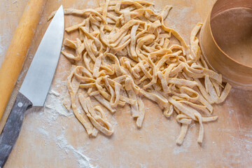 Raw freshly prepared homemade egg noodles on a wooden board - 781234594