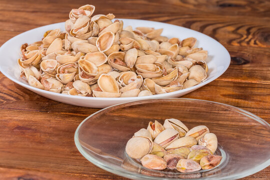 Partly peeled pistachio nuts on saucer against the empty shells
