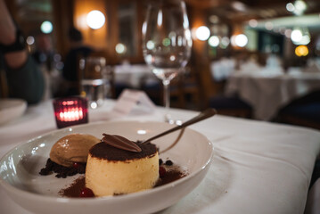 Elegant dessert presentation on white plate with flan, cocoa, chocolate garnish, ice cream, berries...
