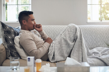 Sick, man and cough with medication for flu, sinus or illness on living room sofa at home. Tired male person lying on lounge couch with fever, influenza or throat infection from bacteria at the house