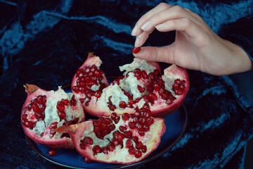 Female hand holds a pomegranate seed. Close-up shot with rich colors and textures. Healthy eating...