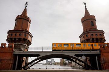 Fototapeta na wymiar Yellow Berlin metro cars moving along the red brick historic bridge